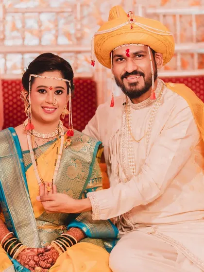 A classic portrait of the happy couple. The bride's yellow and blue saree is a vibrant choice, and her makeup enhances her natural beauty perfectly.