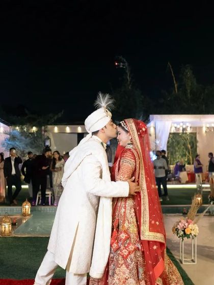 The first kiss as a married couple, a milestone moment captured against the backdrop of their beautiful outdoor wedding venue.