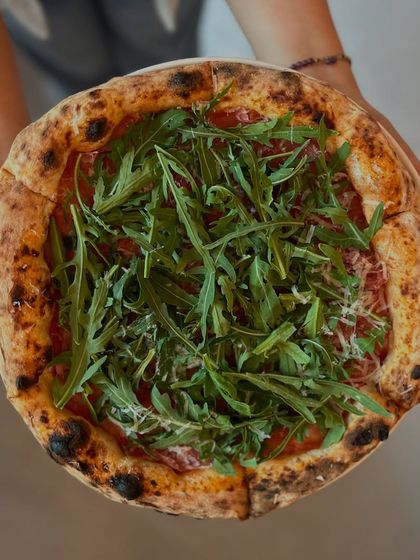 A beautiful overhead shot of our Prosciutto di Parma e Rucola pizza, generously topped with fresh greens.