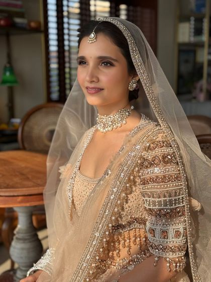 A side profile captured in beautiful natural light. This highlights the dewy finish on her skin and the intricate pearl and thread work on her sleeves.