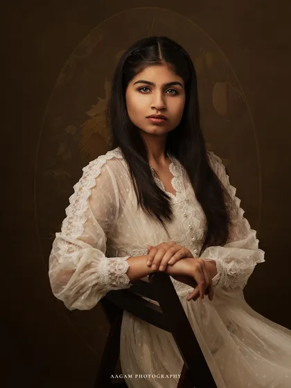 A muse in white lace. The soft, ethereal quality of her dress and the painterly background create a portrait that is both romantic and timeless.