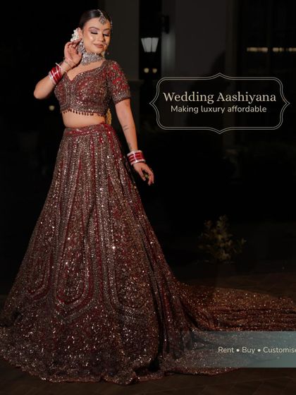A stunning night shot of a bride in a deep maroon lehenga with a long trail. The sequins catch the light beautifully, making it perfect for an evening ceremony or reception.