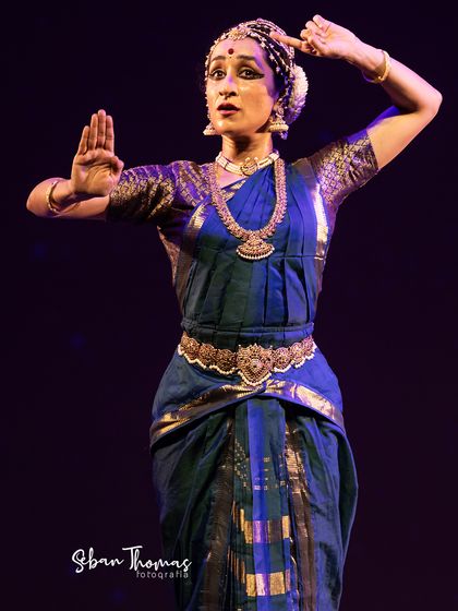 A pose of reverence and offering. The intricate jewelry and headpiece, known as 'talai-saaman', are traditional elements of the Kuchipudi costume.