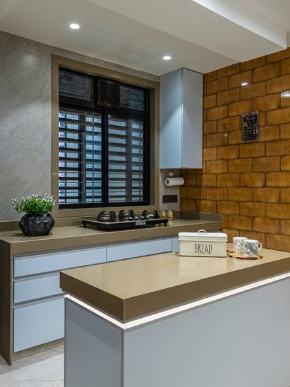 Another view of the Filigree House kitchen, showing the island and ample counter space. The design balances rustic brick with sleek, modern cabinetry for a unique, eclectic feel.