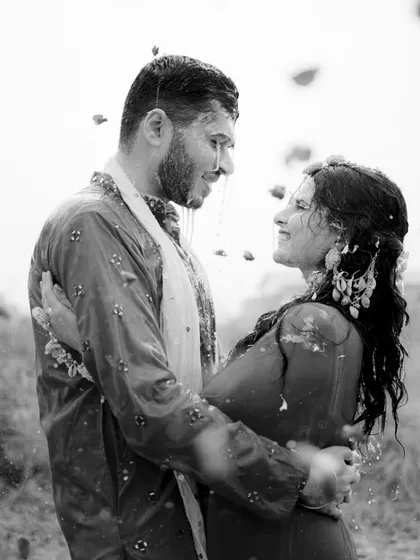 A candid black and white photo of the couple sharing a look as they are showered with water.