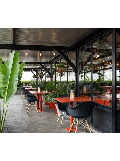 This adaptive event space is designed for flexibility, with lightweight furniture that can be easily rearranged. The open-air terrace, lined with plants, provides a breezy, informal setting for parties and corporate events, connecting the celebration to the surrounding cityscape.