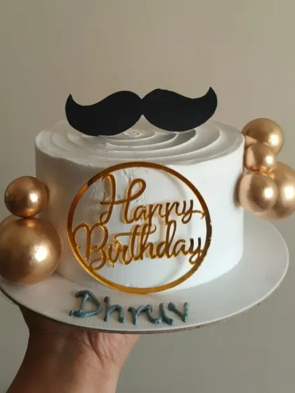 A stylish birthday cake I made for a husband's celebration. It features a fun mustache topper, golden spheres, and a personalized name, making it a great choice for him.
