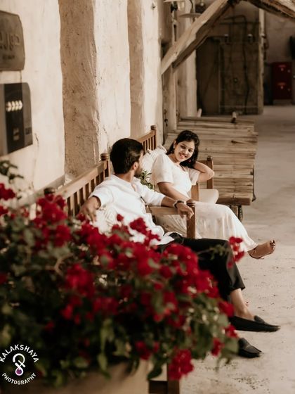 A relaxed and happy moment shared on a bench, with beautiful red flowers adding a pop of color.
