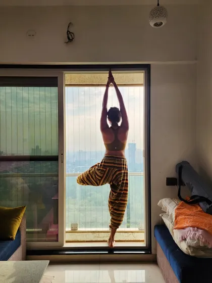 This Tree Pose (Vrikshasana) against a window symbolizes finding balance and stability even amidst the hustle of city life.