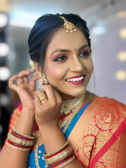 A candid shot showing the bride adjusting her earrings, highlighting the natural and radiant makeup finish.