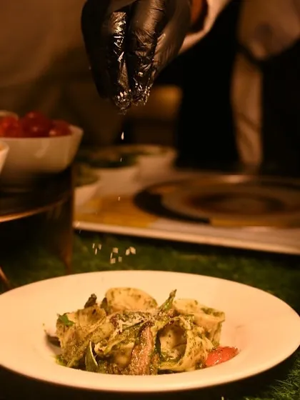 A chef adds the final seasoning to a freshly tossed pasta dish at our live station, ensuring each plate is perfectly seasoned and garnished.