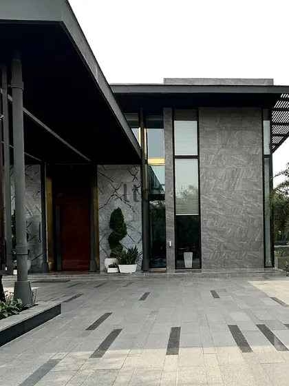 This modern farmhouse exterior is defined by a sophisticated palette of grey stone and dark monochrome tones. The clean lines and large windows create a seamless connection to the outdoors, blending timeless elegance with a contemporary aesthetic.