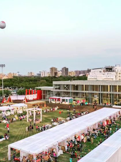 The Glass Pavilion seen from a distance, with a large outdoor market set up, demonstrating its function as a community hub.
