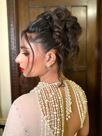 A modern and chic tousled high bun is perfect for a cocktail party or reception. This textured updo keeps the hair elegantly off the face while face-framing tendrils add a touch of softness and movement.