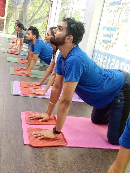 Students hold a cow pose on acupressure mats, combining a spinal stretch with the therapeutic benefits of acupressure.