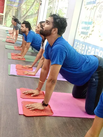 Students hold a cow pose on acupressure mats, combining a spinal stretch with the therapeutic benefits of acupressure.