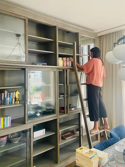 A glimpse of me curating the library shelves in a Dubai home. I believe a library should tell the homeowner's story, so I personally source and style each object, layering books with travel mementos and curios to achieve a perfectly imperfect balance.