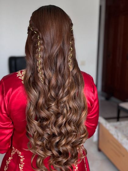 Hair entwined with art. This half-up style features delicate chain braids woven through long, flowing curls for a unique and beautiful look.