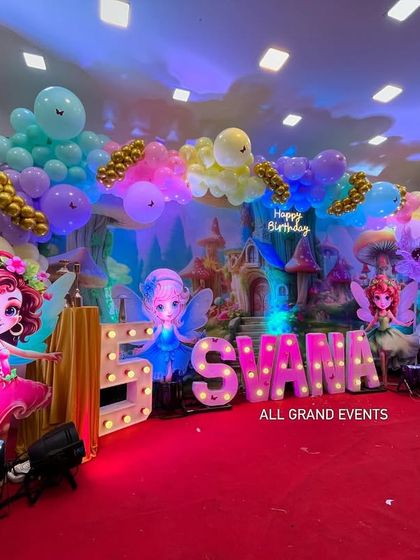 A close-up of the left side of the stage, detailing one of the large, colorful fairy cutouts and the custom balloon arrangement.