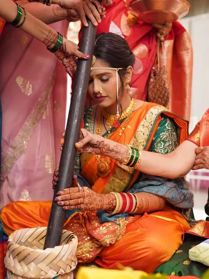 A candid shot during a wedding ritual. The focus is on the bride's serene expression and the traditional elements of her attire.
