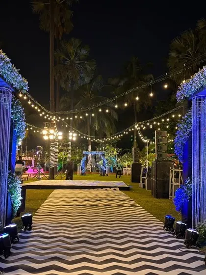 A dramatic entrance for a Sangeet or reception. The walkway features a bold chevron pattern, flanked by crystal-draped pillars and blue lighting for a high-impact, glamorous look.