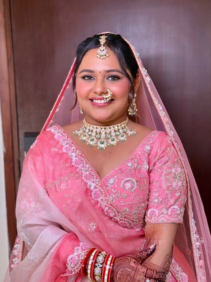 A happy bride in pink. The makeup is kept fresh and radiant, with a soft pink lip and defined eyes to complete the look.