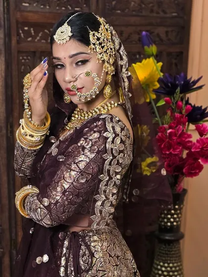 A side profile of the wine-coloured lehenga, highlighting the detailed embroidery on the sleeves and the elegant passa on the side of the head.