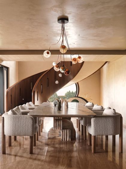 The dining area is positioned to take advantage of the view of the magnificent spiral staircase. The organic form of the chandelier echoes the curves of the stairs, creating a cohesive design narrative.
