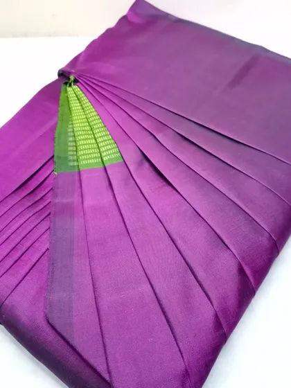 A simple purple saree with a hint of green, pleated neatly.