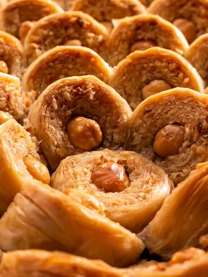 This shot focuses on the unique shape and texture of hazelnut-filled Şöbiyet baklava, showing the variety within the product line.