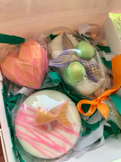 A whimsical gift box containing three different mermaid-themed soaps: a donut soap, a heart soap, and a mermaid tail soap.