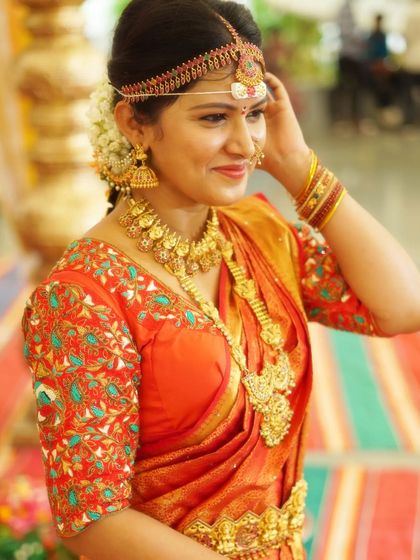 A closer look at the intricate details of our temple jewellery set, paired with a vibrant orange saree. The craftsmanship of the necklace and earrings is clearly visible.