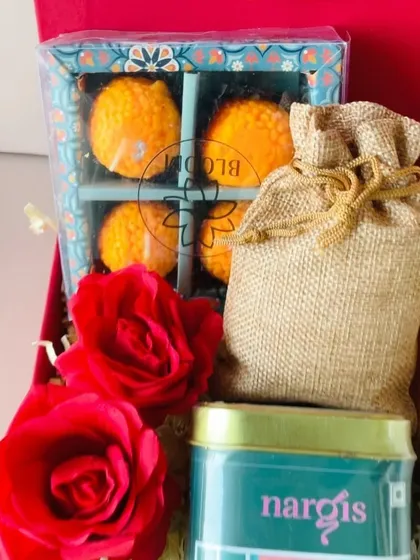 A close-up on the adorable laddoo candles and the jute potli of almonds from the premium red box hamper. It's all in the details.
