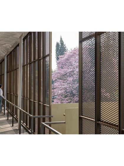 A view from the "Hoverspace" verandah, looking out through the mesh screen to the blooming trees of the campus beyond. The breakout space connects employees with the natural environment.
