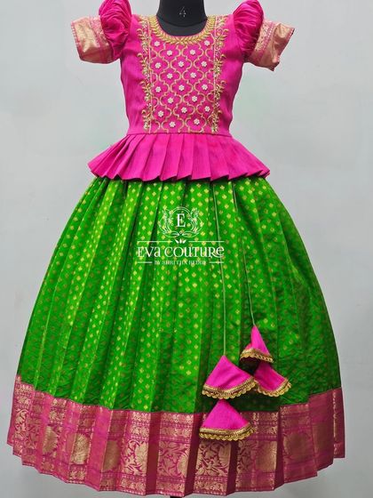 A vibrant green and pink Pattu Pavadai. The blouse has a modern grid embroidery pattern.