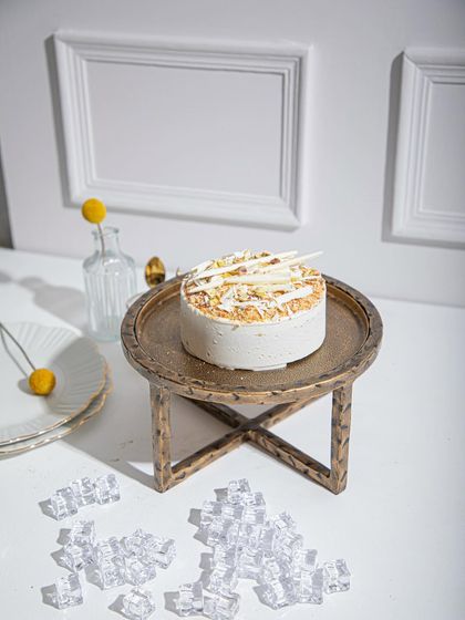 A full view of our Vanilla Raspberry ice cream cake on a golden stand, a picture of elegance and flavour.