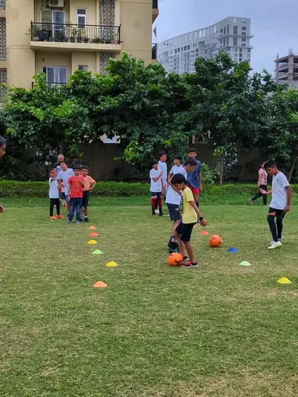 A coach guides young players through a dribbling drill using cones to improve their close control and ability to change direction.