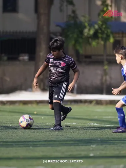 A young player maintains control of the ball under pressure from an opponent.