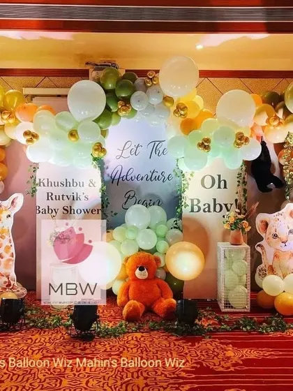 "Let the Adventure Begin" with this jungle-themed baby shower. The decor includes cute giraffe and lion cub props, a warm-toned balloon arch, and a personalized welcome sign.