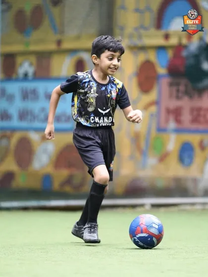 A young player dribbles with a smile, showing that learning new skills can be a joyful experience.