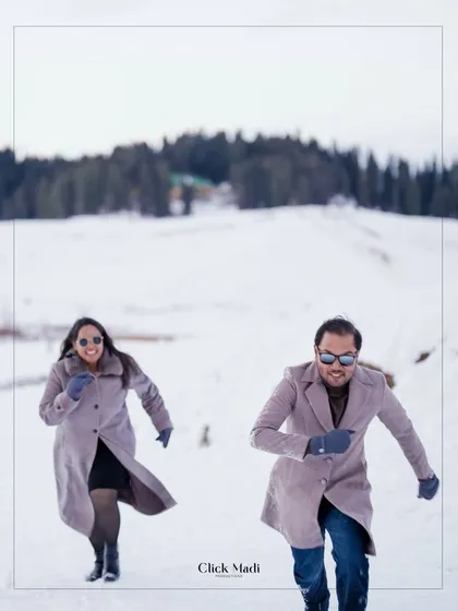 An action shot of the couple running and laughing in the snow, capturing the carefree spirit of their pre-wedding journey in Kashmir.