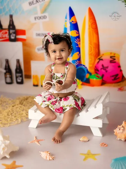 A sweet baby girl enjoys a day at our indoor "beach." This sitter session shows off our detailed beach set, complete with a mini lounge chair, shells, and surfboards.