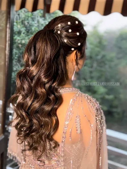 The classic high ponytail with soft curls, this time adorned with scattered pearls for an extra touch of elegance. This shows how a simple accessory can customize the look.