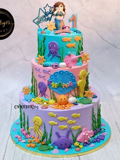 An impressive 8kg, three-tier mermaid-themed cake. This underwater masterpiece is decorated with a fondant mermaid, sea creatures, and colorful coral reefs for a spectacular first birthday.