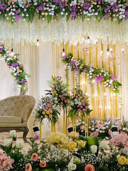 For a soft and romantic reception, I designed this stage with lush pastel florals, elegant chandeliers, and warm lighting. The hanging wisteria and dense flower arrangements create a dreamy, luxurious feel.