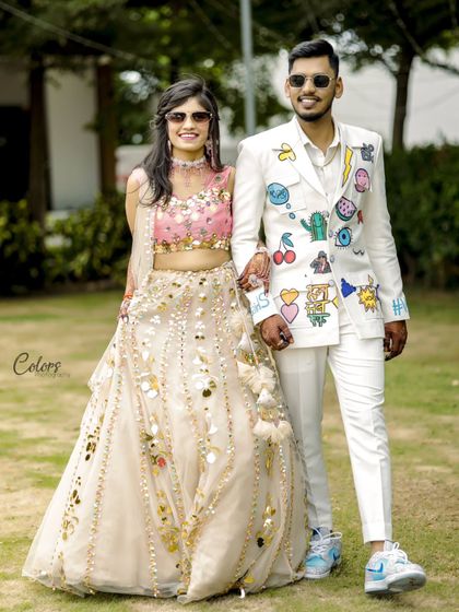 A full-length shot showcasing the couple's quirky and coordinated outfits for their Haldi ceremony, including a hand-painted groom's suit.