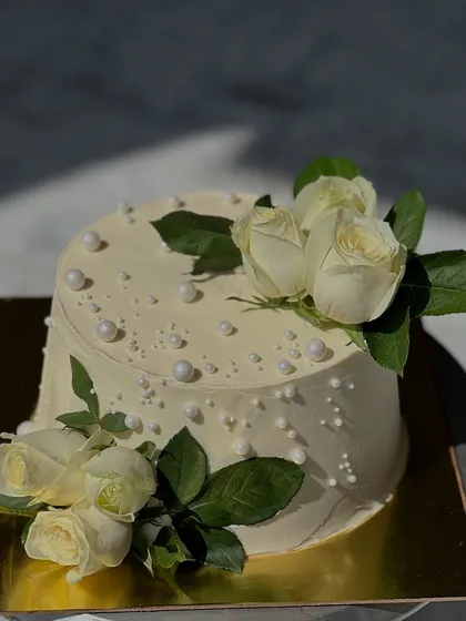 A classic and timeless design featuring fresh white roses on a smooth, pearl-studded frosting. This elegant cake is perfect for any sophisticated celebration, from weddings to anniversaries.