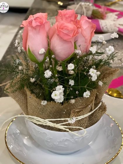 A beautiful floral arrangement in a teacup, wrapped in jute. This close-up shows how simple elements like pink roses and baby's breath can create a charming and personal touch.