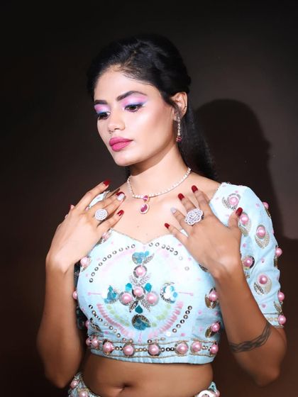 A detailed shot focusing on the eye makeup and jewelry. The pop of pink on the eyes and lips brings the whole look to life, complementing the pastel outfit beautifully.