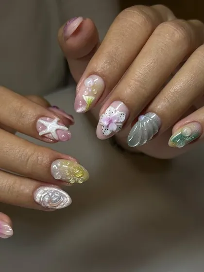 A full view of a whimsical, ocean-inspired nail art set. This design features 3D starfish, shells, and pearls in a variety of pastel colors.